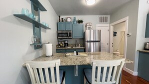 A modern kitchen with teal cabinetry, a stainless steel refrigerator, and a granite countertop. - Jacksonville Towne Square.  (Jacksonville)