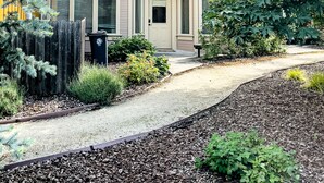 A two-story building with a beige exterior, a front door labeled "180", and a small garden area with mulch and plants. - Jacksonville Towne Square.  (Jacksonville)