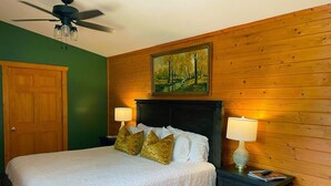 Ein Schlafzimmer mit einem Bett, zwei Nachttischlampen, einem Deckenventilator und einem Gemälde an der Wand.