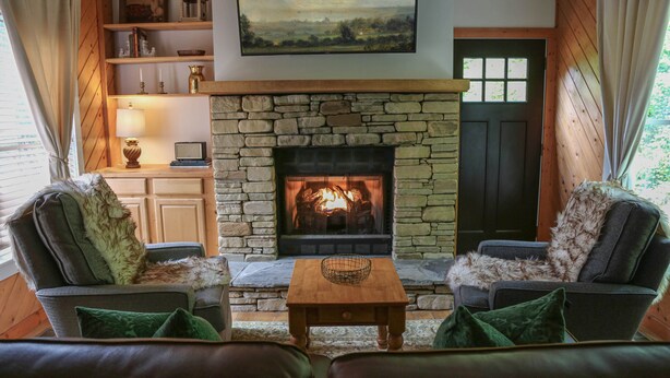 Ein gemütliches Wohnzimmer mit Kamin aus Stein, Ledersofas und einem Holztisch.
