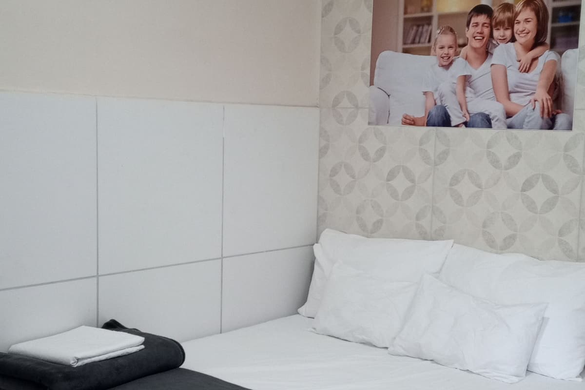 A modern hotel room with a neatly made bed, a large window, and a decorative wall panel.