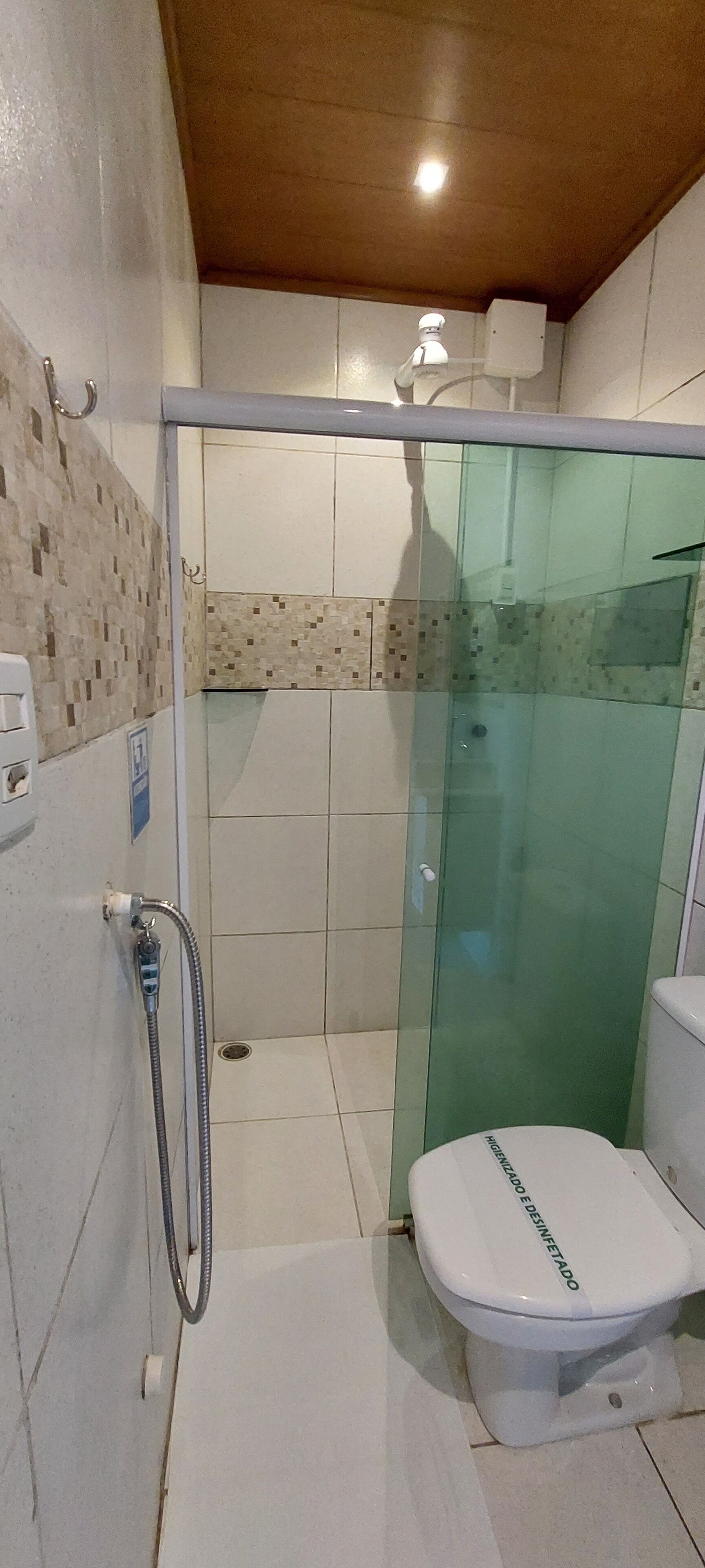 Un baño con cabina de ducha de vidrio, inodoro y ducha de mano.