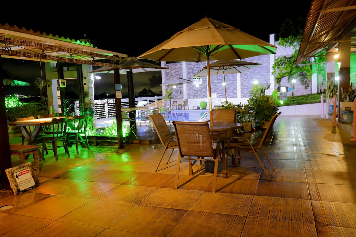 An outdoor patio area with tables and chairs, umbrellas, and potted plants.