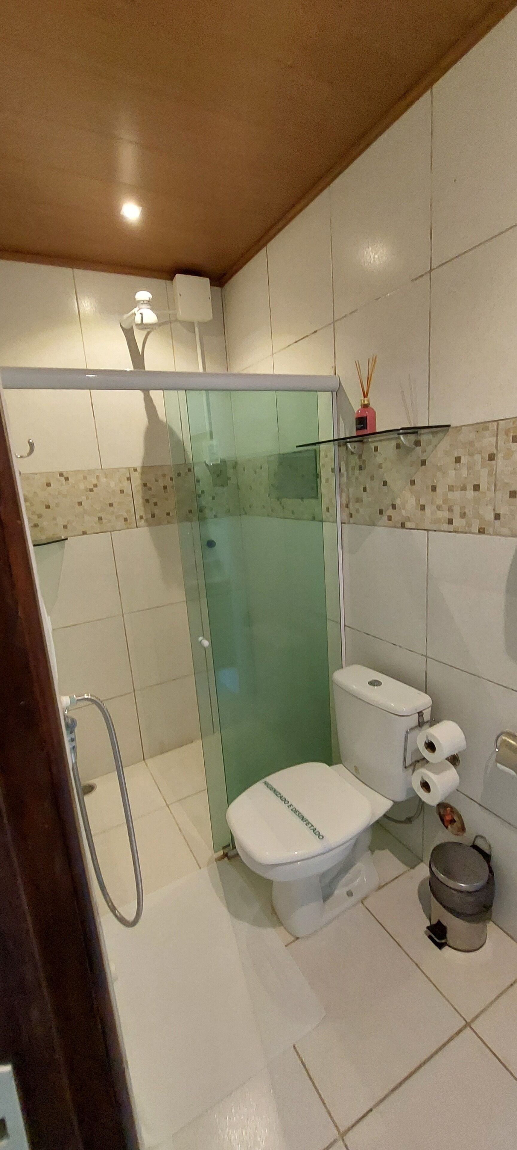 A modern bathroom with a glass-enclosed shower, a toilet, and a trash bin.