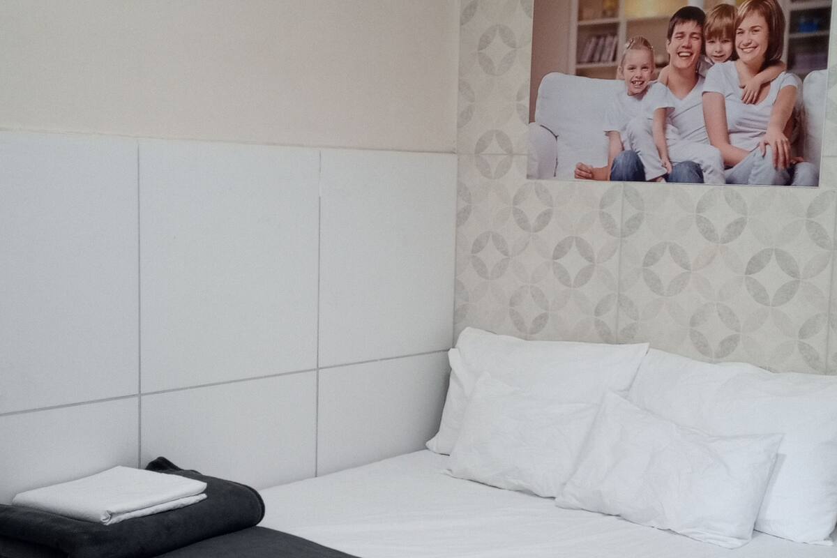 A hotel room with a bed, a pillow, a blanket, and a wall with a patterned wallpaper.