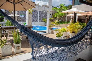 A hammock, a pool, and potted plants in an outdoor area. - Pousada rota do pilão (Araçoiaba)
