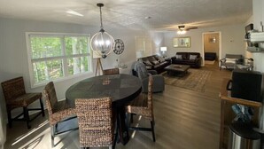A spacious living area with a round dining table surrounded by wicker chairs, a dark sofa, and a coffee table. - Uncork, Unwind, Relax @ this Family & pet Friendly Lake Home #1 (Martin)