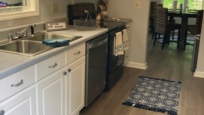 A modern kitchen with white cabinets, stainless steel appliances, and a dining area with a chandelier. - Uncork, Unwind, Relax @ this Family & pet Friendly Lake Home #1 (Martin)