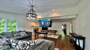 Una sala de estar con chimenea, mesa de billar y televisor montado en la pared.