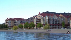 Ein Hotel am Wasser mit mehreren Gebäuden, Balkonen und einem Strandbereich.