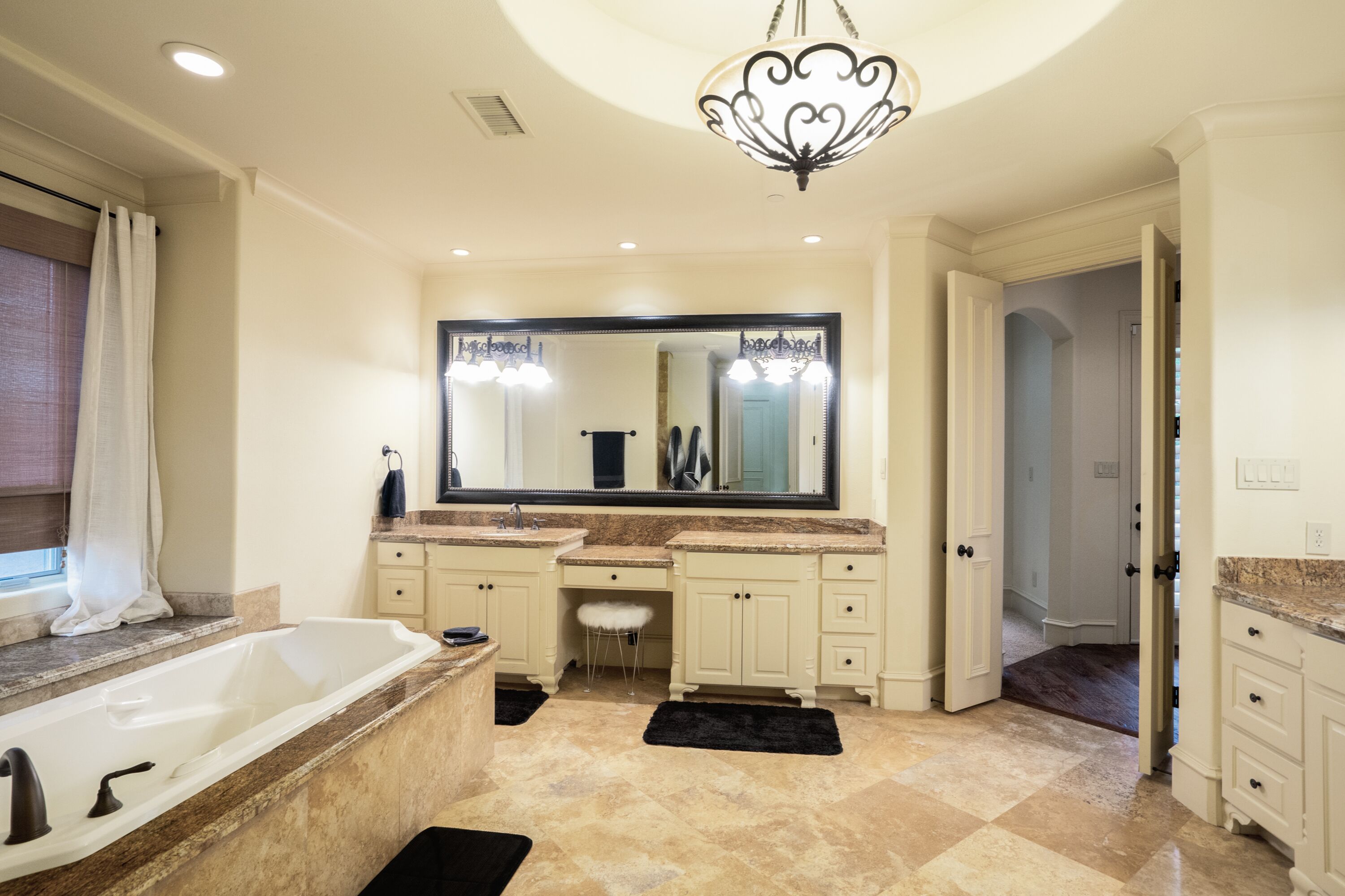 A spacious bathroom with a large vanity, a bathtub, and a mirror above the sink.
