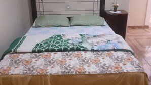 A bed with a patterned bedspread, a headboard, and a nightstand with a plant. - Refúgio da chapada (Cavalcante)
