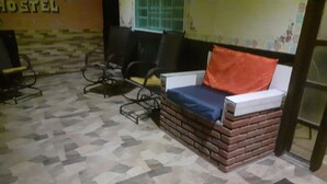 A room with a brick-patterned sofa, a tiled floor, and a wall with a partial view of a sign. - Refúgio da chapada (Cavalcante)