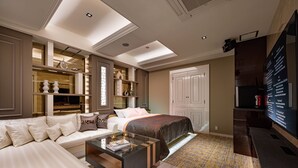 A modern bedroom with a large bed, a sofa, a glass coffee table, and built-in shelving. - HOTEL K-NEXT (Saitama)
