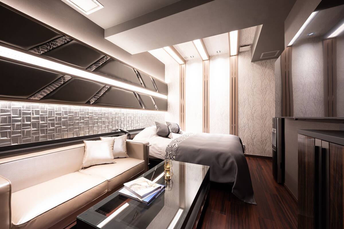 Un dormitorio moderno y bien iluminado con un sofá, una cama y una mesa de vidrio.