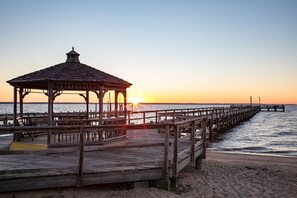 Eine hölzerne Mole, die sich in ruhiges Wasser bei Sonnenuntergang erstreckt.