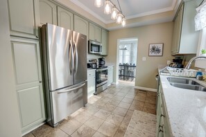 A modern kitchen with stainless steel appliances, light green cabinets, and a large island with a sink.