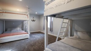 A room with bunk beds, a ladder, and a chandelier. - Holiday Haven | 7BR Sleeps 24 | Private Pickleball Court, Lake Views & Beach Access (Garden City)