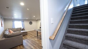 A living room with a sofa, a table, and a clock on the wall. - Holiday Haven | 7BR Sleeps 24 | Private Pickleball Court, Lake Views & Beach Access (Garden City)
