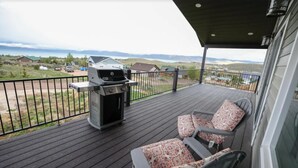 A covered deck with a grill, outdoor seating, and a view of the landscape. - Holiday Haven | 7BR Sleeps 24 | Private Pickleball Court, Lake Views & Beach Access (Garden City)