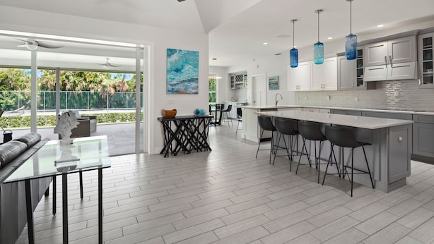 A modern kitchen with a central island, bar stools, and pendant lighting.