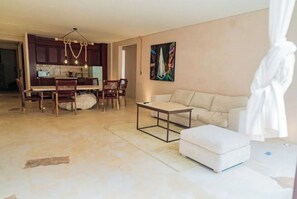 Una sala moderna con sofá, reposapiés, mesa de centro y comedor con sillas y mesa.