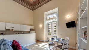 Un espacio habitable compacto con kitchenette, comedor y televisor montado en la pared.