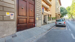 Un edificio con una puerta de madera grande, un cartel de no estacionamiento y un coche aparcado en la calle.