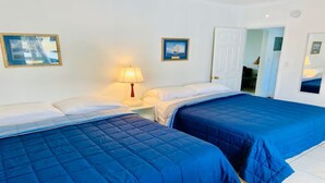 A hotel room with two beds, a nightstand, a lamp, and framed pictures on the walls.