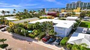 A coastal hotel with multiple buildings, a parking area, and a view of the ocean.