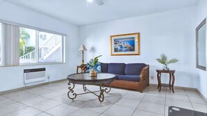 A spacious living room with a blue sofa, a round coffee table, and a framed picture on the wall.