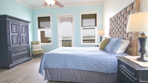 Une chambre à coucher avec un lit, une commode, une chaise et une vue par la fenêtre.