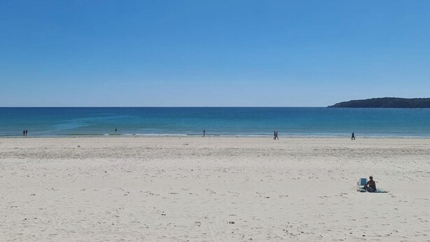 Een strand met een heldere lucht en een rustige zee.