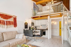 Un appartement moderne de style « loft », comprenant un coin repas, une cuisine et un escalier menant à un niveau supérieur.