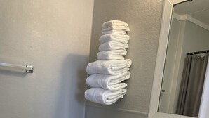 A bathroom with a toilet, sink, and a stack of towels on the wall. - Sunset Motel (Lake City)