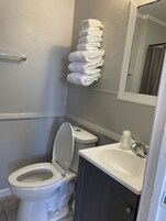 Bañera con ducha, toallas, jabón, shampoo