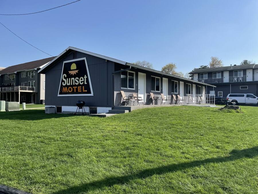 Un motel con un letrero grande, mesas al aire libre y un césped.