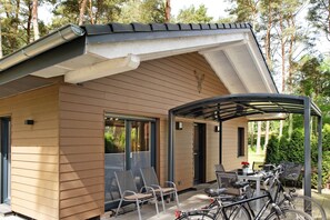 Une maison moderne dotée d’un patio couvert, d’un espace salon extérieur et de vélos.