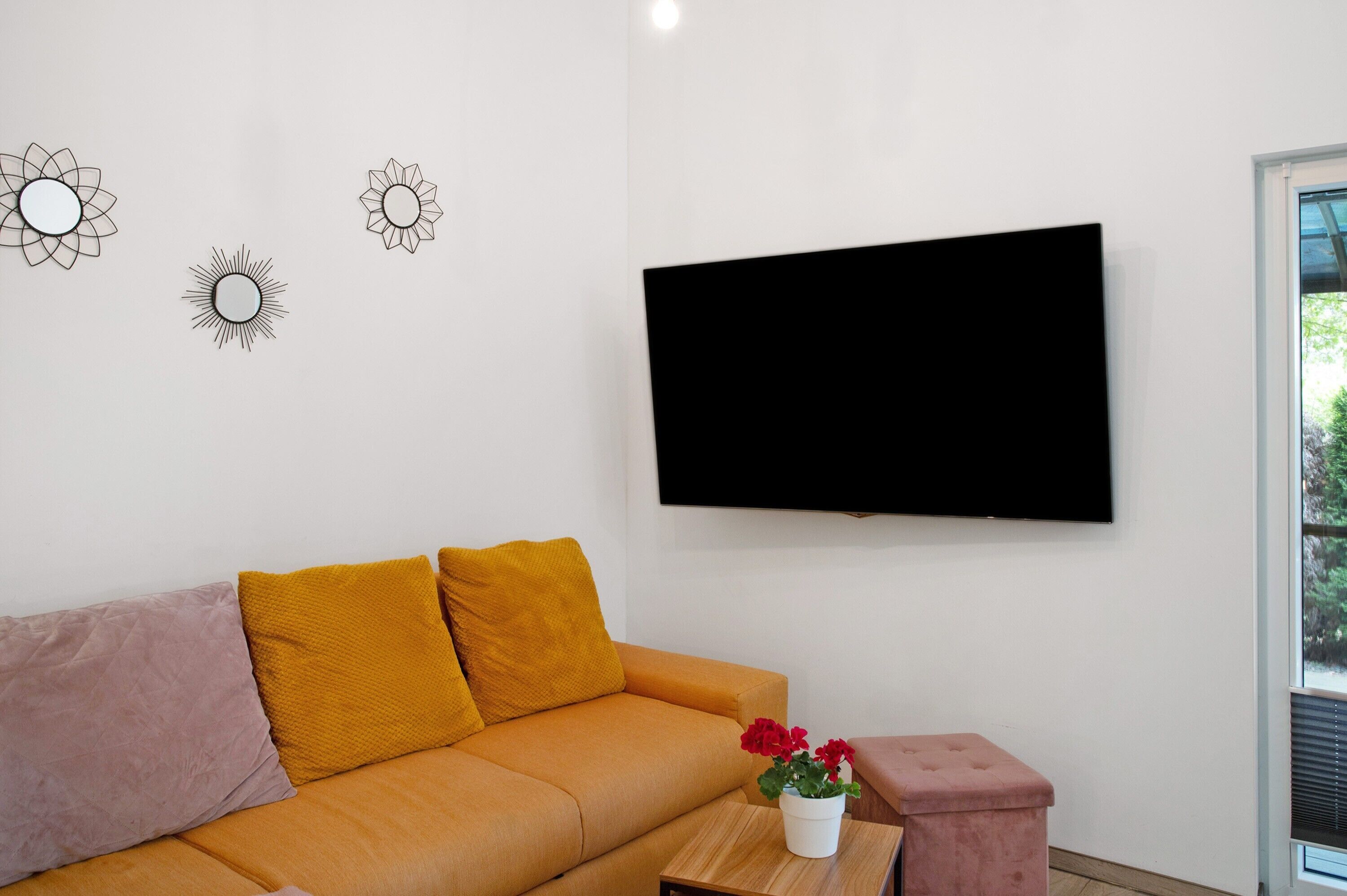 Un saló amb un sofà, una televisió i elements decoratius a la paret.