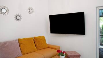 Un saló amb un sofà, una televisió i elements decoratius a la paret.