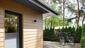 Una casa moderna con fachada de madera, puerta corredera y terraza pavimentada.