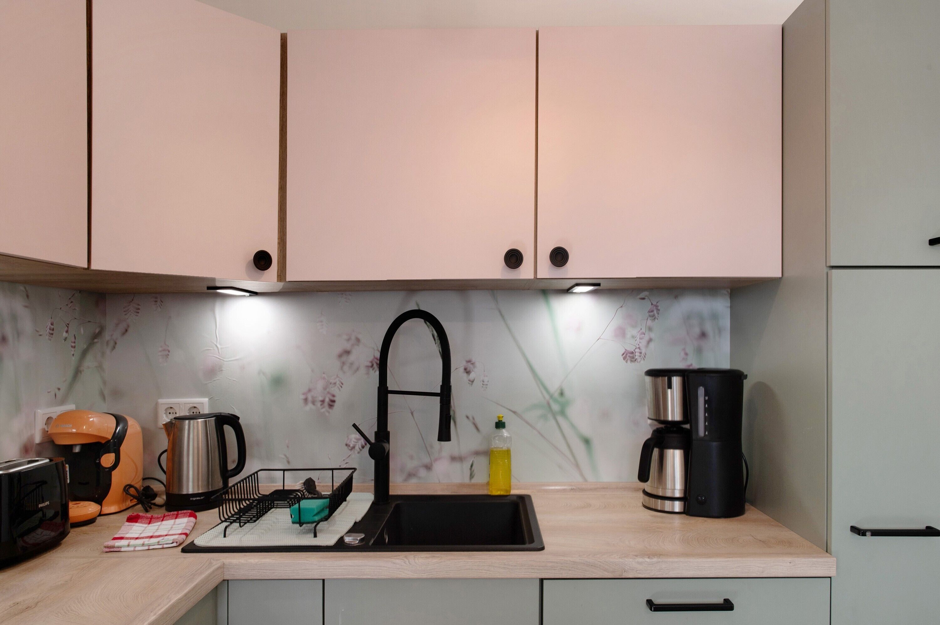 A kitchen with a sink, a coffee maker, a kettle, and a toaster.