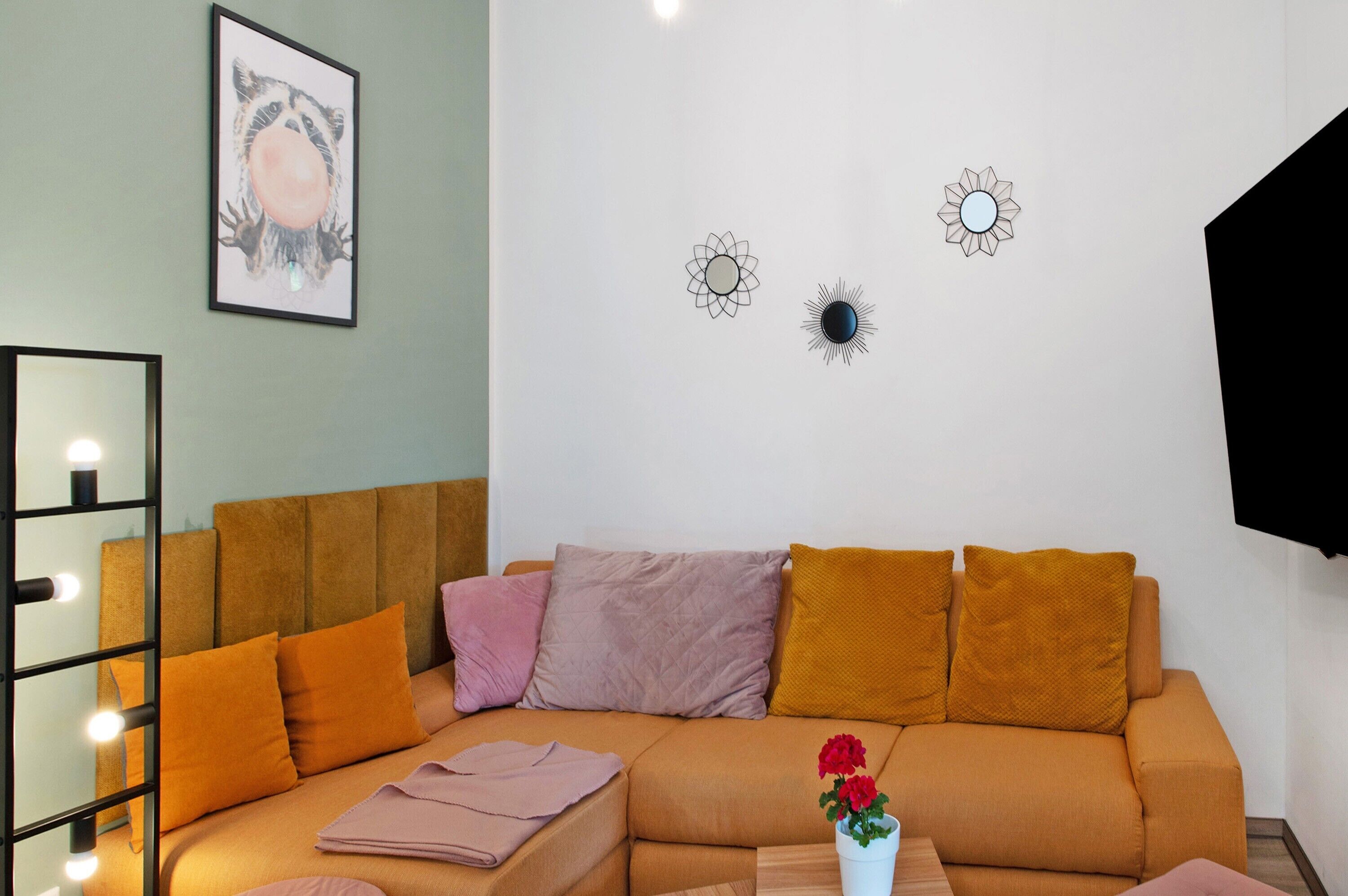 A room with a sofa, pillows, a mirror, and wall decorations.