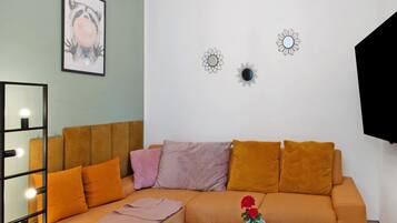 A room with a sofa, pillows, a mirror, and wall decorations.