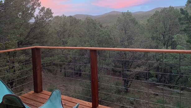 A wooden deck with a metal railing overlooking a forested landscape. - Scenic cabin in Carson National Forest (Ranchos de Taos)