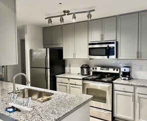 A modern kitchen with stainless steel appliances, a granite countertop, and white cabinetry. - 2Bedroom Luxury Vacation Home & Free Parking (Sandy Springs)