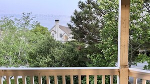 A wooden deck with a view of a house surrounded by trees.