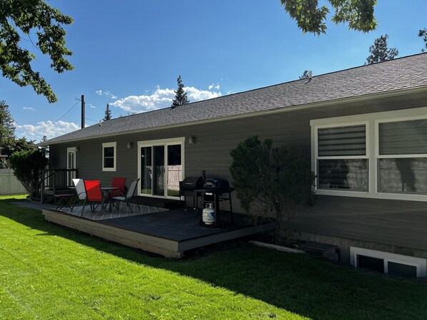 Une maison d’habitation dotée d’un patio couvert, d’un barbecue et d’un petit jardin.