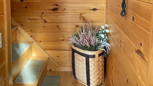 En inredning med träpanel, en trävägg, en telefon, en korg med blommor och ett trappsteg med en matta.