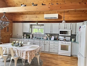 A cozy kitchen with wooden beams, white cabinets, a central island, and a hanging light fixture. - Charming 3 bedroom on Beech Hill Pond close to Ellsworth and Bar Harbor WiFi, AC (Otis)